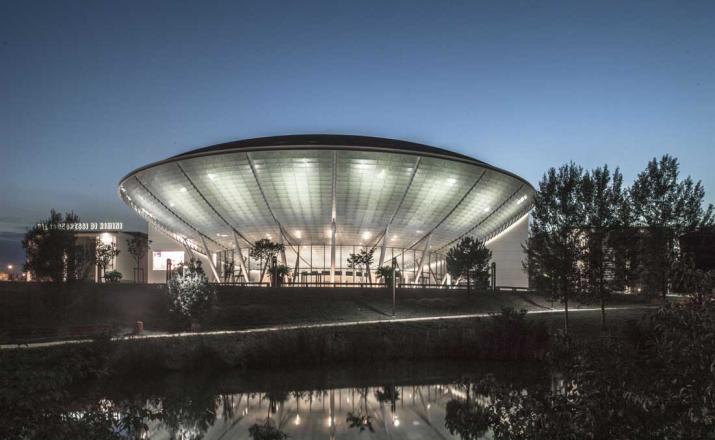 Edificio moderno con tetto illuminato, riflesso nell'acqua.